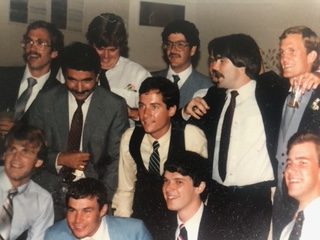 Brothers in jackets and ties crowded together at an indoor event