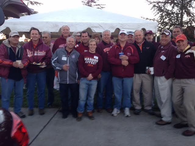 A large group in maroon and orange under a tailgate tent